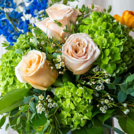 Bouquet of peach roses, green hydrangeas, and blue flowers