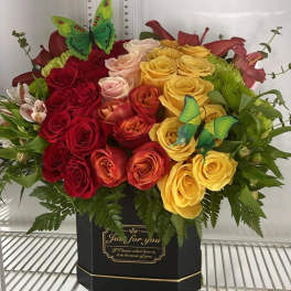 Bouquet of red, yellow, and blush roses in a black box with butterfly picks.