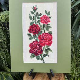 Framed embroidery of red roses on a green mat board