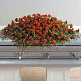 Long casket spray of orange carnations arranged on a closed gray casket