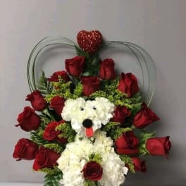 Red roses and white flowers arranged with a teddy bear face and heart topper