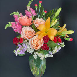 Mixed bouquet of roses, lilies, and snapdragons in a glass vase