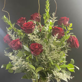 Red roses in a clear glass vase with a pink ribbon