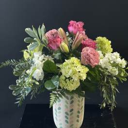 Pink and white floral arrangement in a patterned vase