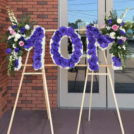 Purple and white floral letters on wooden easels outside a building