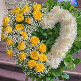 Two large floral heart wreaths on easels, one yellow and one white