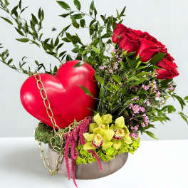 Red roses and orchids arranged with a heart decoration in a round box
