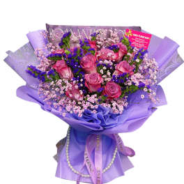 Pink roses with purple filler flowers wrapped in lavender paper