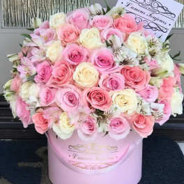 Pink and white roses arranged in a round pink box