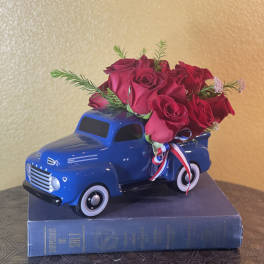 Red roses arranged in a blue toy truck on top of a book