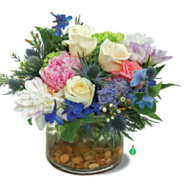Mixed bouquet of roses, daisies, and blue flowers in a glass vase