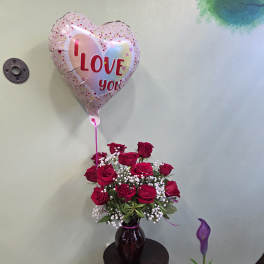 Red rose bouquet in a vase with a heart-shaped "I love you" balloon