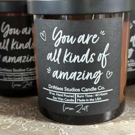 Black jar candle with a label reading "You are all kinds of amazing"