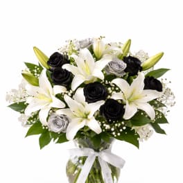 Bouquet of white lilies and black roses in a glass vase