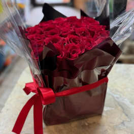 Bouquet of red roses wrapped in dark paper with a red ribbon