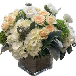 Cream roses and white hydrangeas in a square glass vase