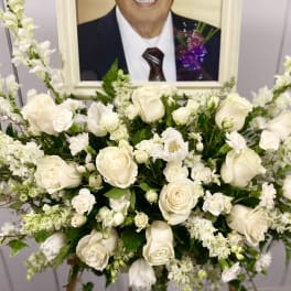 White rose and snapdragon arrangement in front of a framed portrait