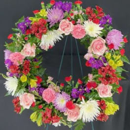 Colorful floral wreath on a stand with pink, red, purple, and white blooms