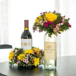 Two wine bottles with floral arrangements around them