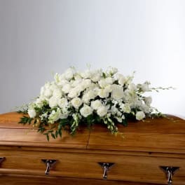 White floral spray arranged on a wooden casket