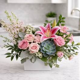 Pink roses and a lily arranged in a white rectangular vase