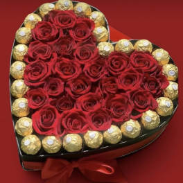 Heart-shaped box of red roses surrounded by gold-wrapped chocolates