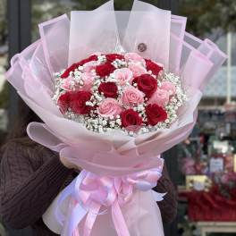 Bouquet of red and pink roses wrapped in pink paper with a ribbon