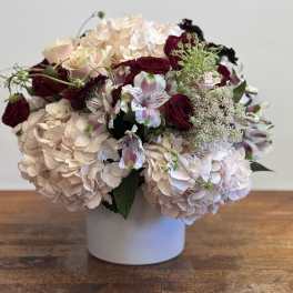 Bouquet of pale hydrangeas and burgundy roses in a white vase