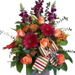 Bouquet of orange roses, red gerberas, and purple snapdragons in a wooden box