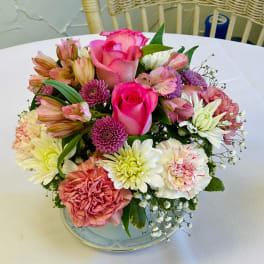 Pink roses and mixed blooms arranged in a low dish on a table