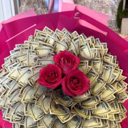 Bouquet of pink roses surrounded by folded dollar bills in bright pink wrapping