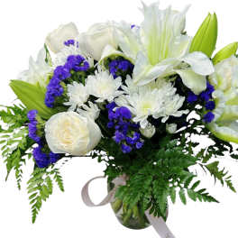 White lilies and roses with purple accents in a glass vase