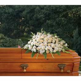 White floral casket spray on a wooden coffin