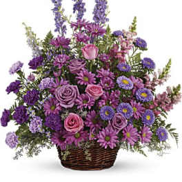 Purple and pink mixed flower arrangement in a wicker basket