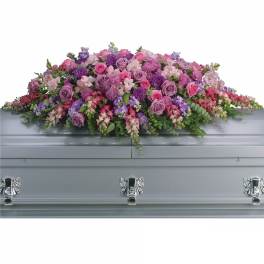 Large pink and purple floral casket spray on a silver casket