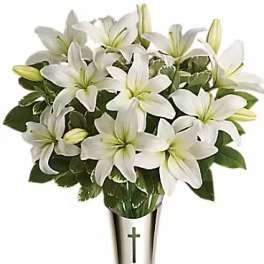 White lilies arranged in a silver vase with a cross emblem