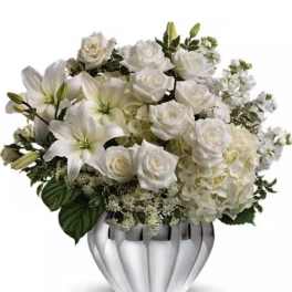 White roses and lilies arranged in a silver vase