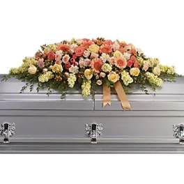 Pastel floral casket spray on a silver casket