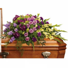 Purple and lavender flowers arranged on a wooden casket