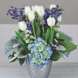 White tulips and blue flowers in a silver vase