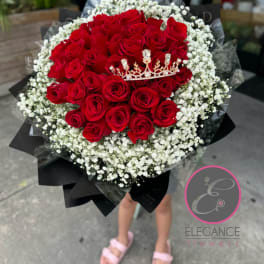 Bouquet of red roses with white baby's breath and a small crown topper