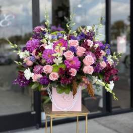 Large pink and purple floral arrangement in a pink gift bag