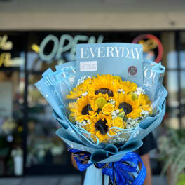 Bouquet of sunflowers and yellow roses wrapped in blue paper