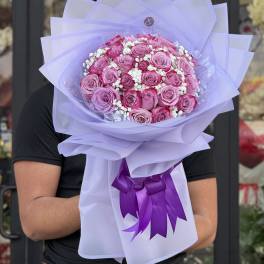 Bouquet of pink roses wrapped in lavender paper with a purple ribbon
