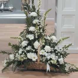 White floral basket arrangement with tall spikes and a white ribbon