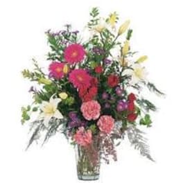 Tall mixed bouquet in a clear glass vase with pink, white, and yellow flowers