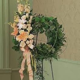 Floral wreath with pale flowers and pink ribbon on a stand