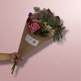 Handheld bouquet of pink roses and purple flowers wrapped in brown paper