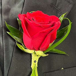 Red rose boutonniere pinned to a black suit jacket