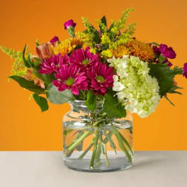 Mixed bouquet of pink and yellow flowers in a clear glass vase